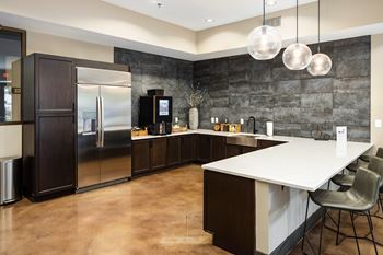 A modern kitchen with a long white island and dark wood cabinets.